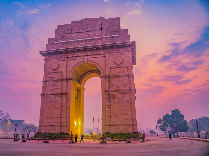 India Gate illuminated in warm evening light under a deep blue sky in New Delhi
